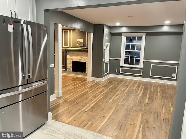 kitchen with light wood-type flooring, a fireplace, freestanding refrigerator, and recessed lighting