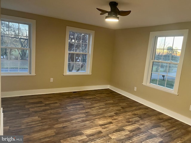 spare room with dark wood-type flooring, baseboards, and a ceiling fan