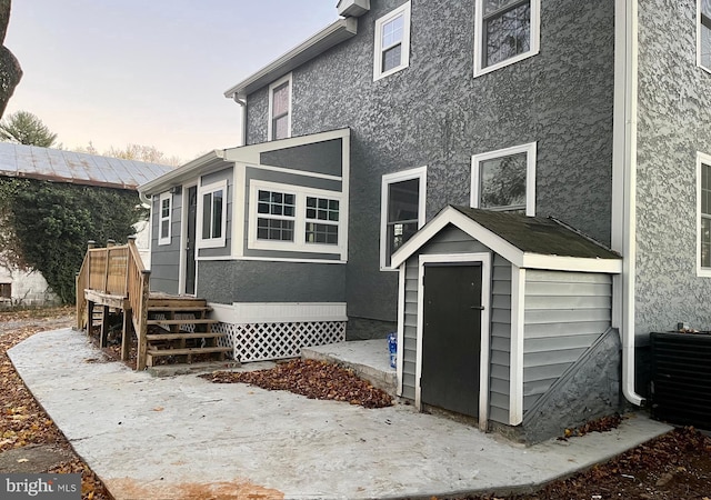 rear view of house featuring a storage unit, central AC unit, an outbuilding, and stucco siding