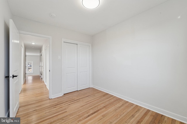 unfurnished bedroom featuring baseboards, a closet, and light wood finished floors