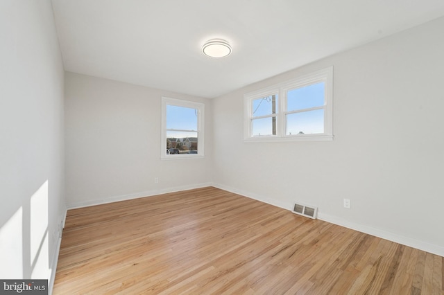 empty room with visible vents, baseboards, and wood finished floors