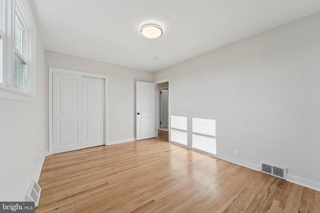 unfurnished bedroom featuring a closet, visible vents, light wood-style flooring, and baseboards