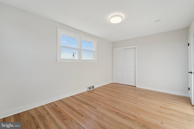 unfurnished bedroom with visible vents, baseboards, a closet, and light wood-style flooring