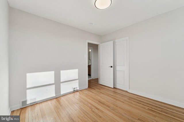 unfurnished bedroom featuring a closet, visible vents, baseboards, and hardwood / wood-style floors