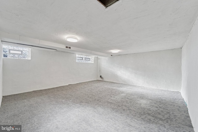 basement with carpet flooring, a healthy amount of sunlight, and visible vents