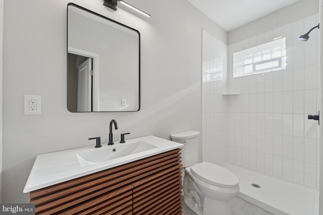 bathroom featuring tiled shower, toilet, and vanity