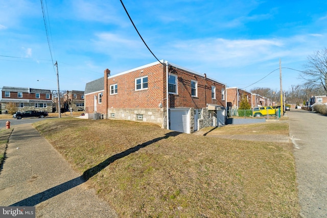 view of side of property with brick siding, a residential view, a lawn, and a garage