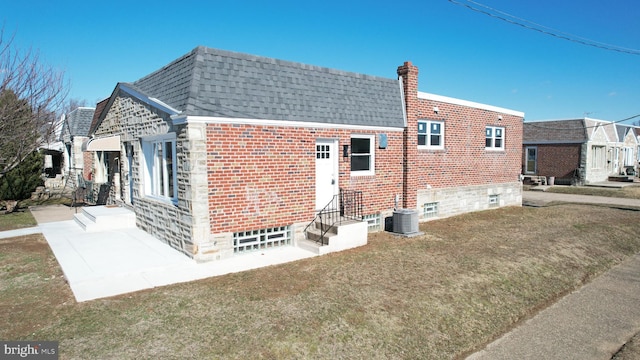 rear view of house with a chimney, brick siding, and a shingled roof