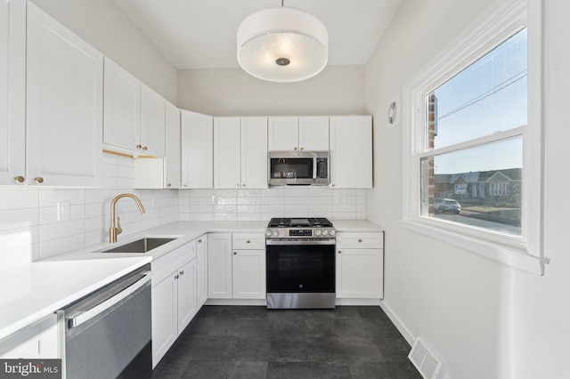 kitchen featuring visible vents, backsplash, white cabinets, stainless steel appliances, and a sink