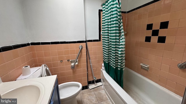 bathroom with tile patterned flooring, toilet, vanity, tile walls, and shower / bath combo with shower curtain