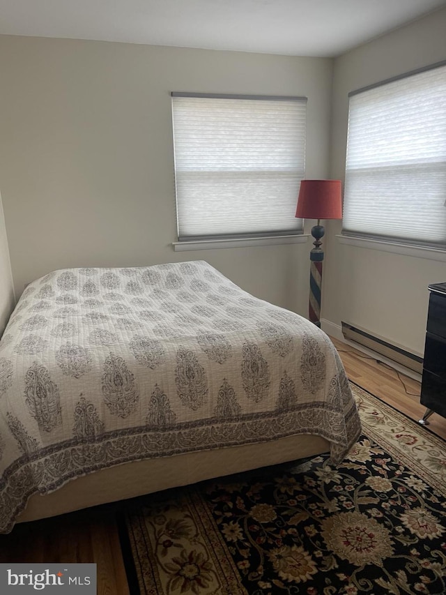 bedroom with a baseboard heating unit and light wood-type flooring