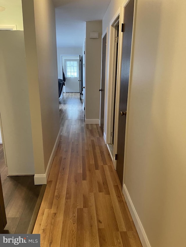 hallway featuring baseboards and wood finished floors