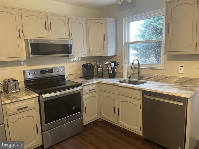 kitchen with dark wood-type flooring, a sink, light countertops, appliances with stainless steel finishes, and decorative backsplash