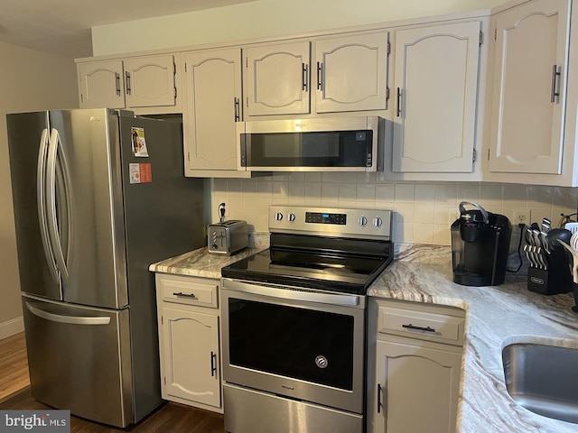 kitchen with a sink, appliances with stainless steel finishes, dark wood-type flooring, and backsplash