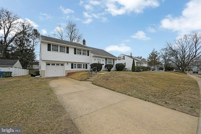 view of front of home with driveway, a front lawn, a chimney, and fence