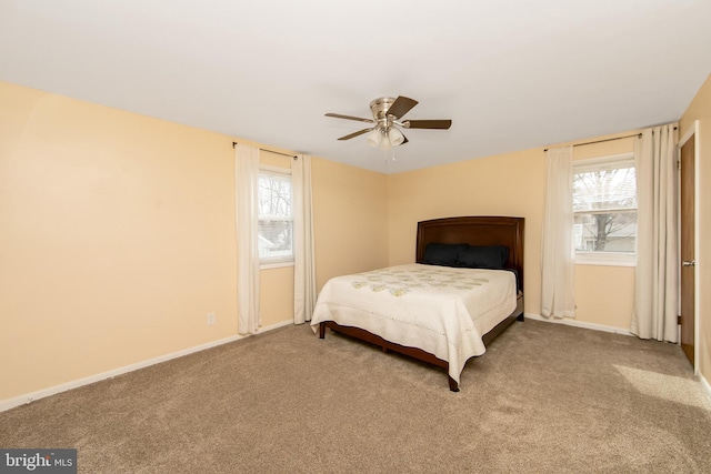 carpeted bedroom with ceiling fan, multiple windows, and baseboards