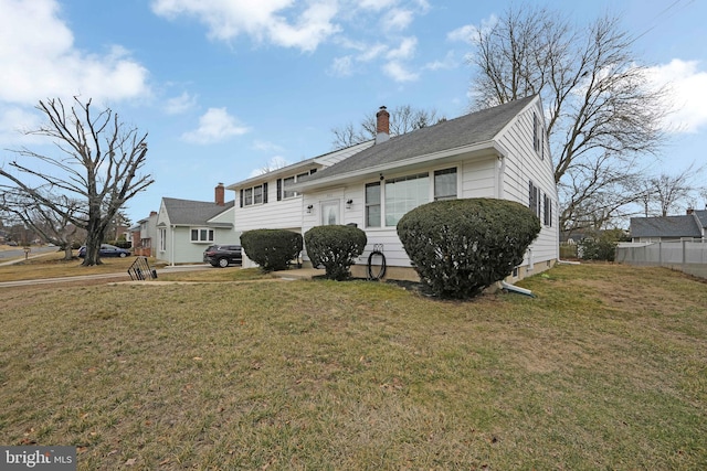 split level home featuring a chimney, fence, and a front yard