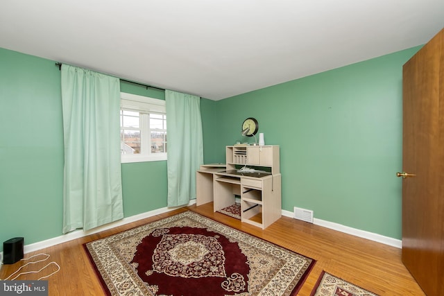 home office featuring visible vents, baseboards, and wood finished floors