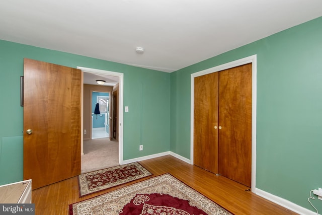 bedroom featuring a closet, wood finished floors, and baseboards