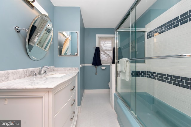 bathroom featuring toilet, baseboards, combined bath / shower with glass door, and vanity