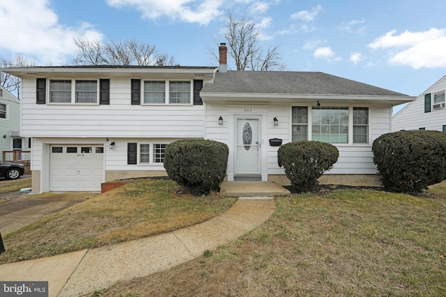 tri-level home featuring a garage, a chimney, a front lawn, and roof with shingles