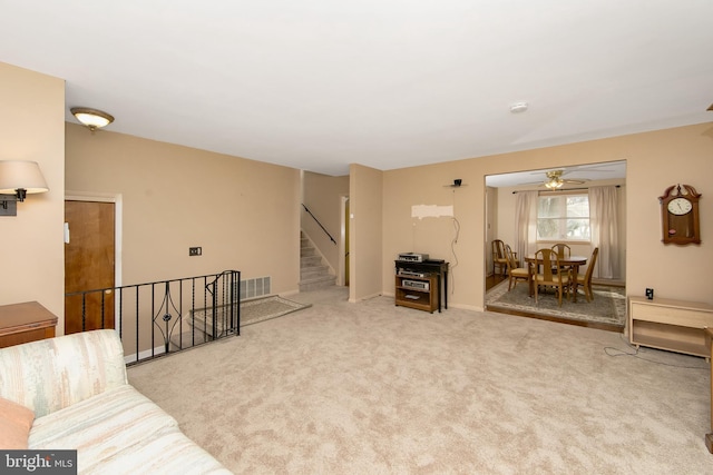 sitting room with stairs, carpet, visible vents, and baseboards