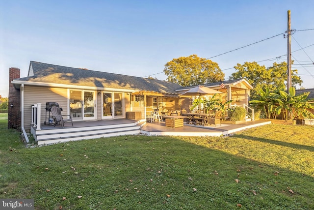 back of property with a chimney, a patio, and a yard