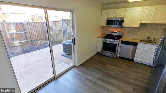 kitchen featuring appliances with stainless steel finishes, dark wood-style flooring, white cabinetry, and tasteful backsplash