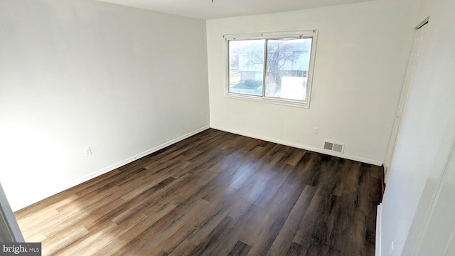 spare room with dark wood-style floors, baseboards, and visible vents