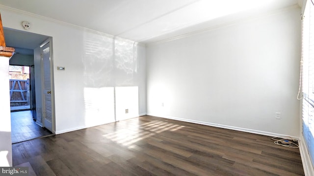 spare room with dark wood-style floors, crown molding, and baseboards