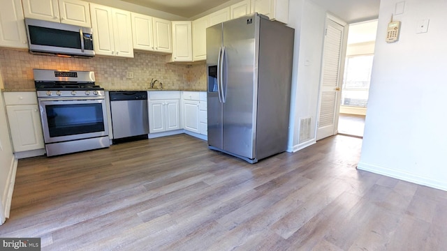 kitchen with stainless steel appliances, decorative backsplash, visible vents, and white cabinets