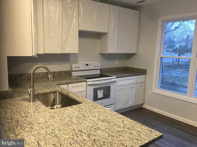 kitchen featuring baseboards, white electric range, a sink, and white cabinets