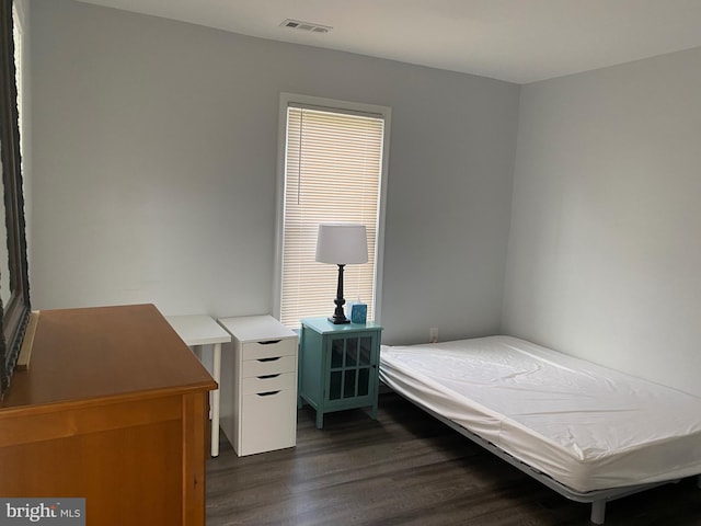 unfurnished bedroom featuring dark wood-style floors, multiple windows, and visible vents