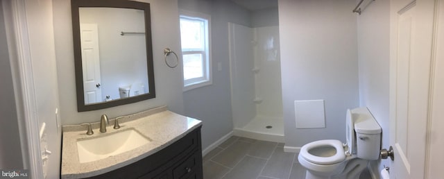 bathroom featuring baseboards, vanity, toilet, and walk in shower