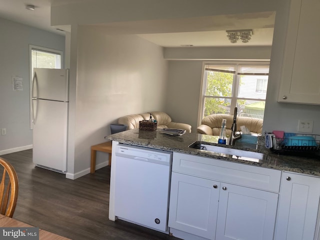 kitchen featuring dark stone counters, white appliances, a sink, and a healthy amount of sunlight