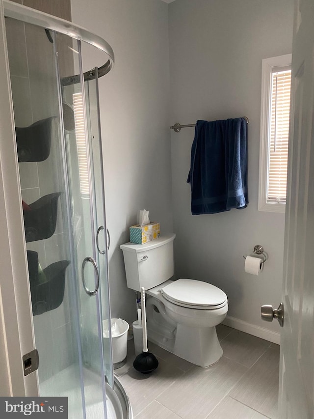 full bathroom featuring a shower stall, toilet, and baseboards