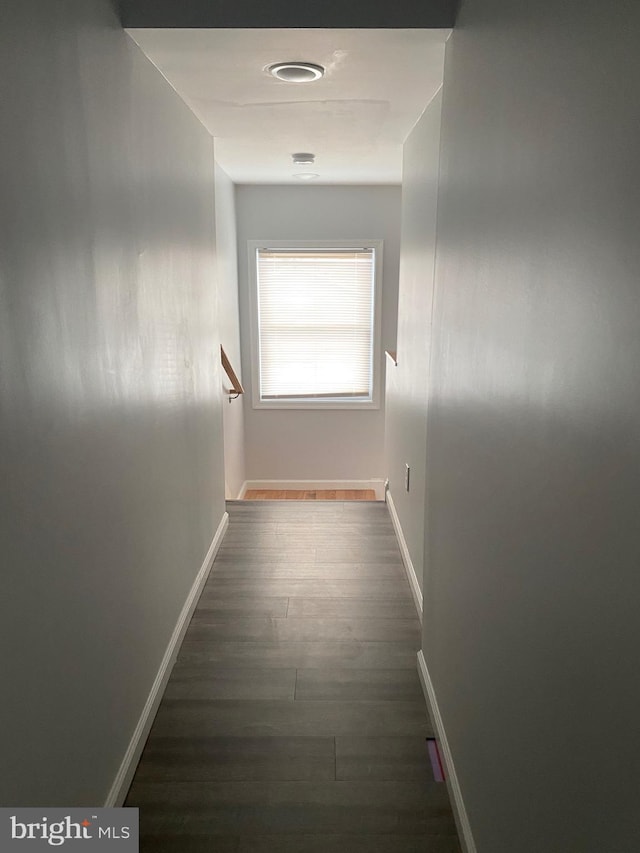 hallway featuring dark wood-type flooring and baseboards