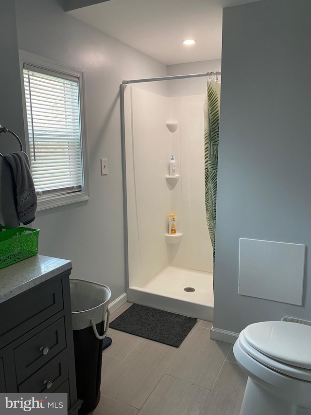 full bath with vanity, a shower stall, toilet, and baseboards