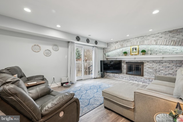 living room with baseboards, brick wall, wood finished floors, a fireplace, and recessed lighting