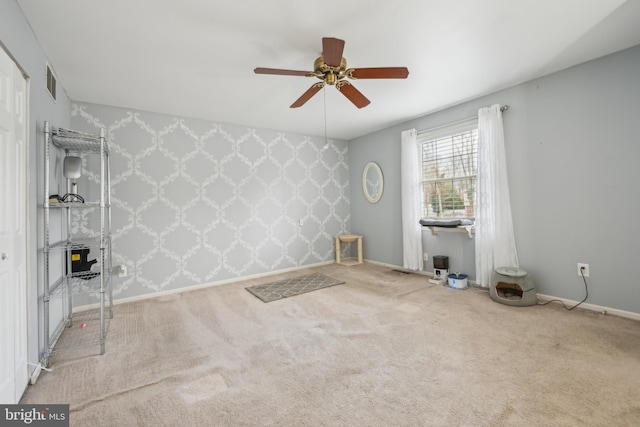 carpeted empty room featuring baseboards, an accent wall, visible vents, and wallpapered walls