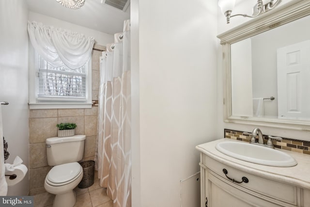 bathroom with tile patterned flooring, toilet, vanity, visible vents, and tile walls