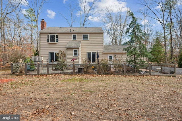 rear view of property with a chimney, fence, and central AC