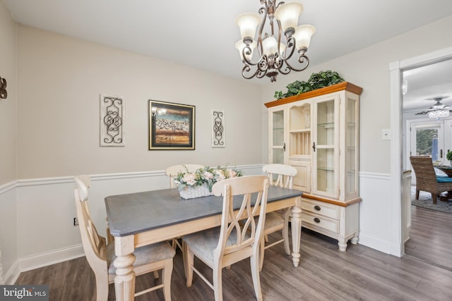 dining space featuring ceiling fan with notable chandelier, baseboards, and wood finished floors