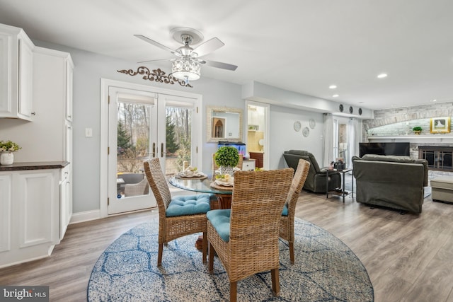 dining area featuring baseboards, french doors, light wood-style floors, a fireplace, and recessed lighting