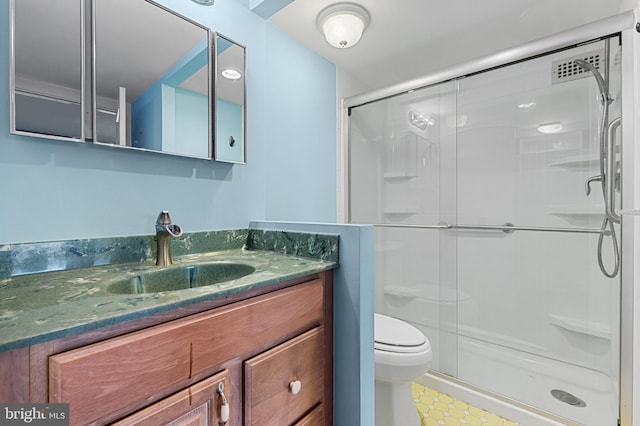 bathroom featuring vanity, a shower stall, and toilet