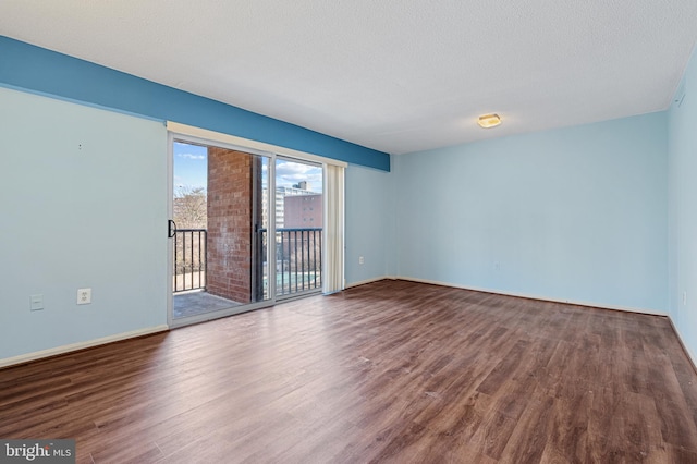 unfurnished room with a textured ceiling, baseboards, and wood finished floors