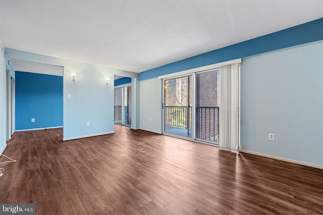 unfurnished living room featuring a textured ceiling, wood finished floors, and baseboards