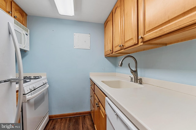 kitchen with white appliances, dark wood finished floors, a sink, and light countertops