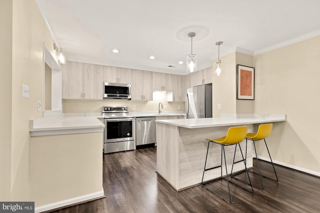 kitchen with a peninsula, a sink, ornamental molding, stainless steel appliances, and a kitchen breakfast bar