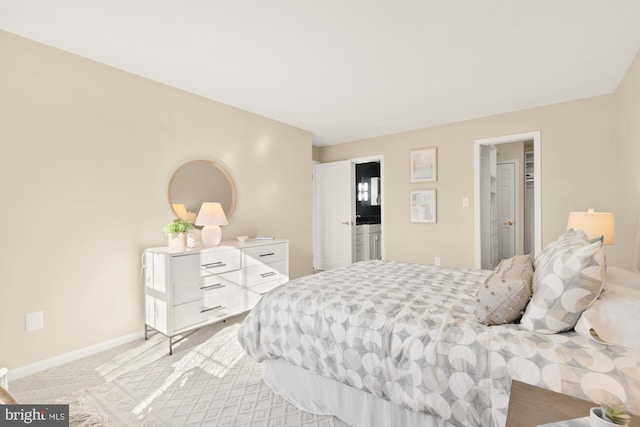 bedroom featuring a walk in closet, baseboards, and light colored carpet